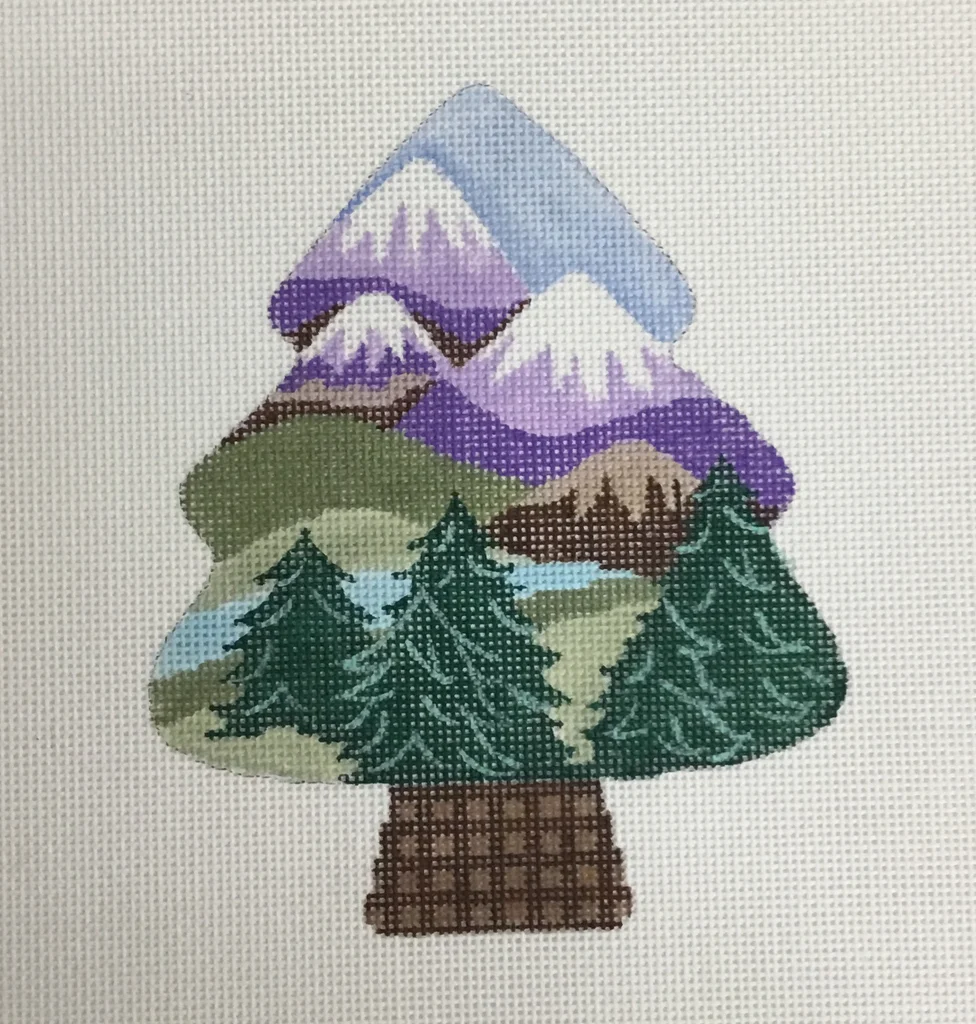 Needlepoint canvas shaped like a tree, depicting a mountain and forest landscape scene in purple, green, blue and brown