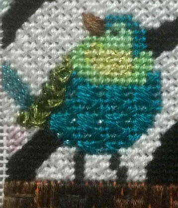 Needlepoint artwork of a blue and green bird.