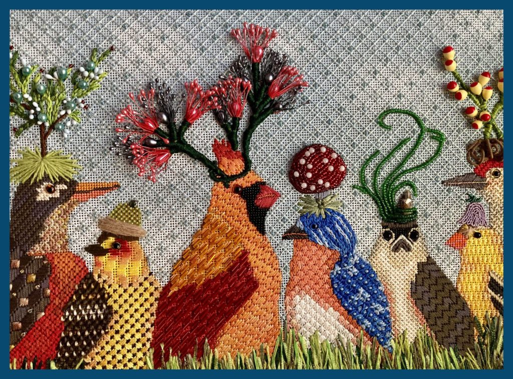 Needlepoint artwork of multicolored birds wearing plant-inspired hats.